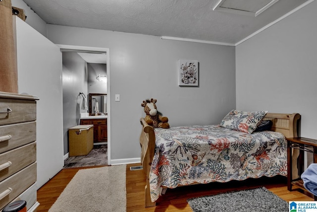 bedroom featuring light hardwood / wood-style floors, a textured ceiling, and ensuite bathroom