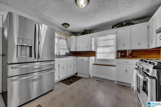 kitchen with stainless steel appliances, white cabinetry, and a textured ceiling