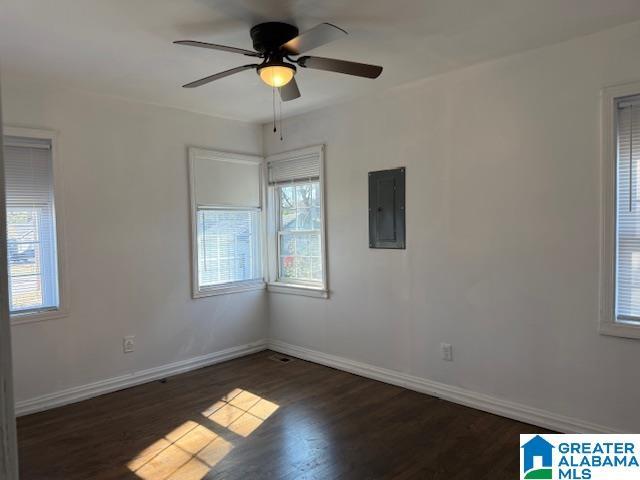 empty room with dark wood-type flooring, ceiling fan, and electric panel