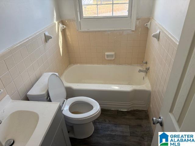 bathroom with wood-type flooring, tile walls, and toilet