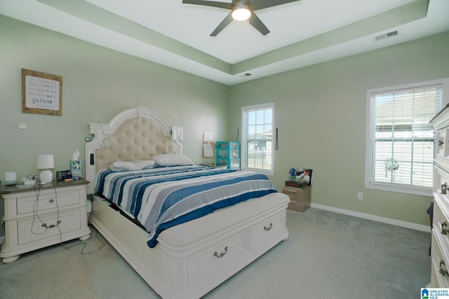 carpeted bedroom featuring ceiling fan and a tray ceiling