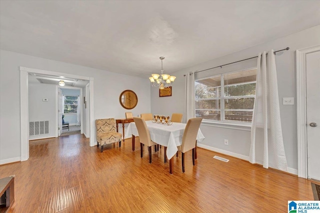 dining area with hardwood / wood-style floors and a notable chandelier