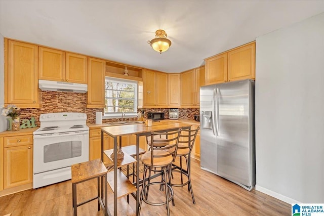 kitchen featuring white electric range, stainless steel fridge, and light brown cabinets