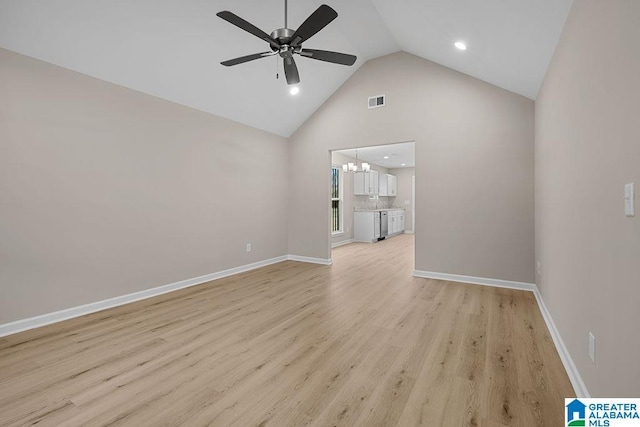 unfurnished living room with high vaulted ceiling, ceiling fan with notable chandelier, and light wood-type flooring