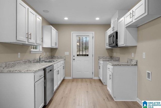 kitchen featuring stainless steel appliances, white cabinetry, sink, and light hardwood / wood-style flooring