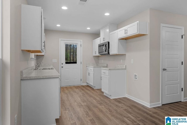 kitchen with white cabinetry, sink, and light wood-type flooring