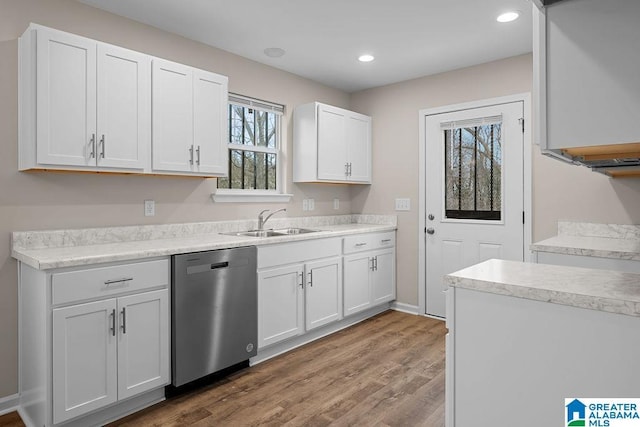 kitchen with white cabinetry, stainless steel dishwasher, light hardwood / wood-style floors, and sink