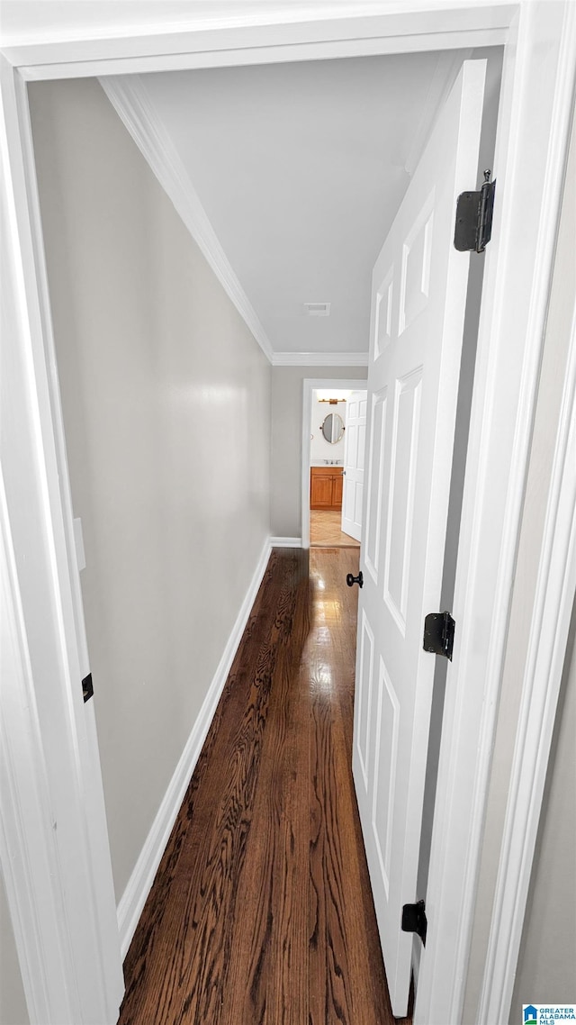 corridor with dark wood-type flooring and crown molding