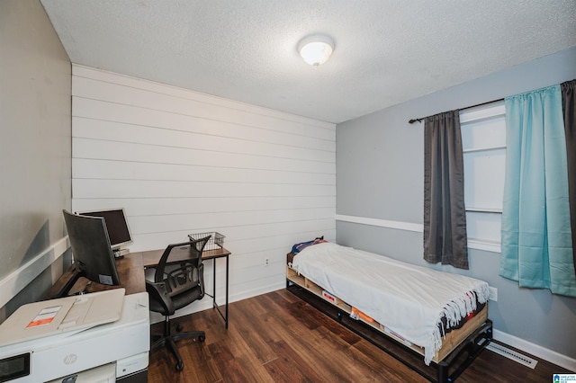 bedroom featuring multiple windows, dark hardwood / wood-style floors, and a textured ceiling