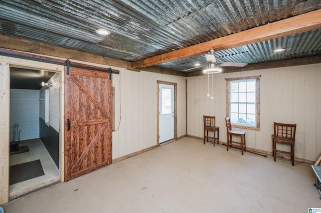 basement featuring a wealth of natural light, wooden walls, and a barn door