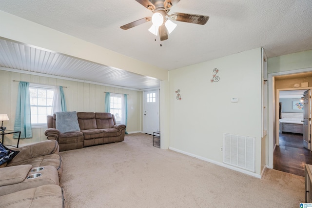 carpeted living room featuring a textured ceiling and ceiling fan