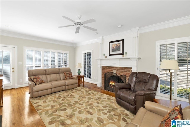 living room featuring ornamental molding, light wood-type flooring, ceiling fan, and a fireplace