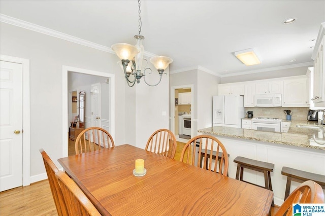 dining space featuring crown molding, sink, light hardwood / wood-style flooring, and a notable chandelier