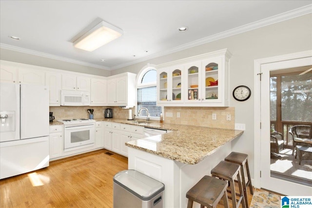 kitchen featuring sink, kitchen peninsula, white appliances, decorative backsplash, and white cabinets