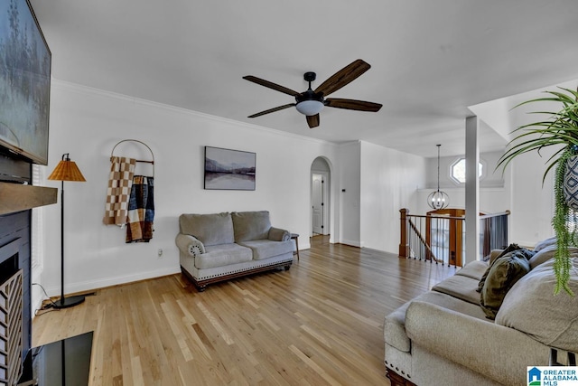 living room featuring crown molding, ceiling fan with notable chandelier, and light hardwood / wood-style flooring