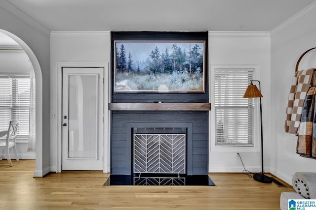 interior details with wood-type flooring, a large fireplace, and crown molding