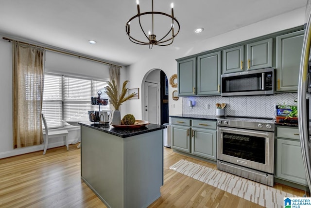 kitchen featuring backsplash, stainless steel appliances, a center island, a notable chandelier, and light wood-type flooring