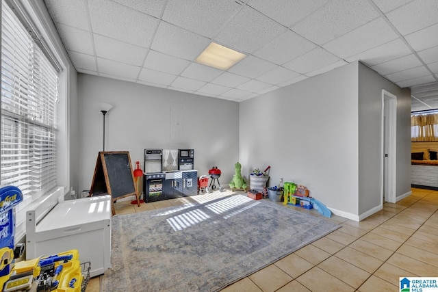 recreation room with a paneled ceiling and light tile patterned floors