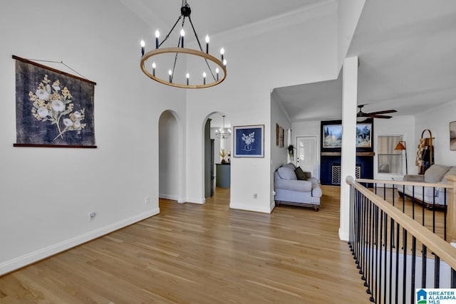 interior space with ceiling fan with notable chandelier, ornamental molding, and light hardwood / wood-style floors