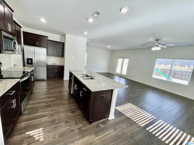 kitchen with sink, stainless steel appliances, dark hardwood / wood-style flooring, and a kitchen island with sink