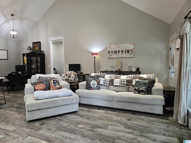 living area featuring high vaulted ceiling, wood finished floors, and a notable chandelier