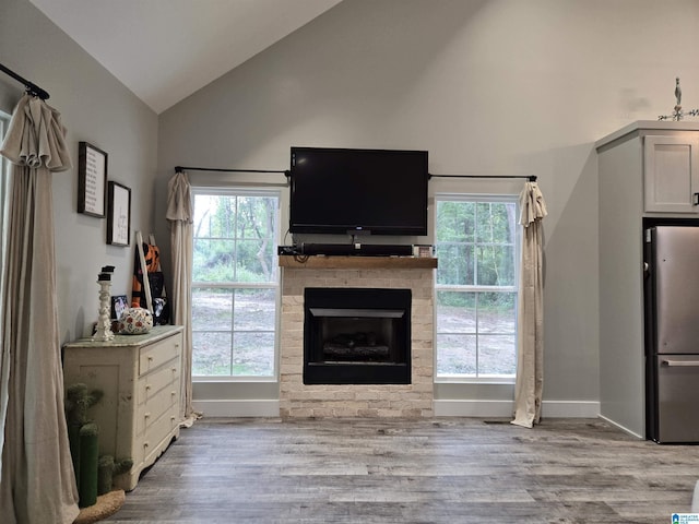 living room with baseboards, plenty of natural light, a fireplace, and light wood-style floors