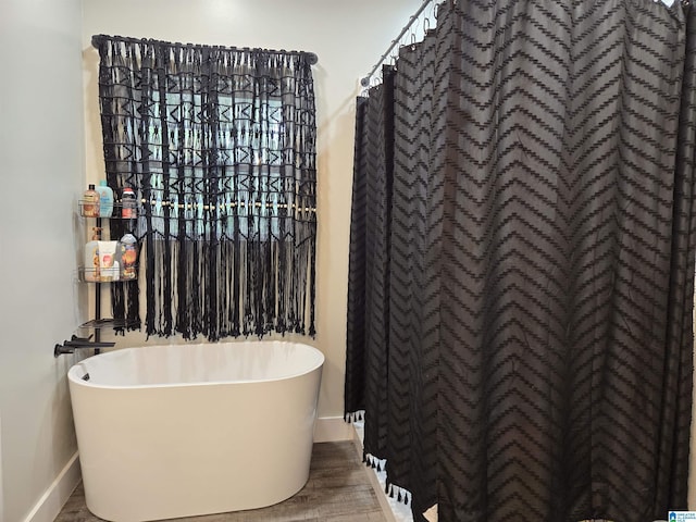 bathroom with a soaking tub and baseboards