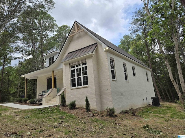 view of side of property with metal roof, central AC unit, and a standing seam roof