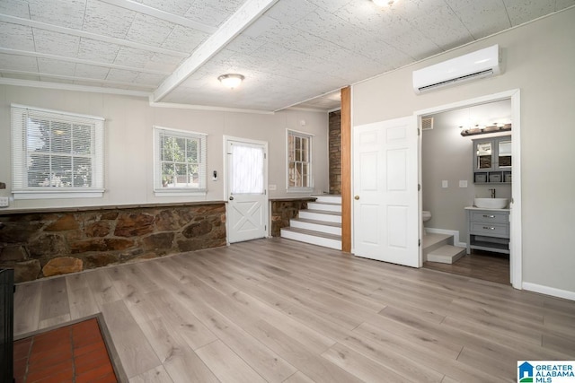 unfurnished living room featuring vaulted ceiling, an AC wall unit, and light hardwood / wood-style flooring