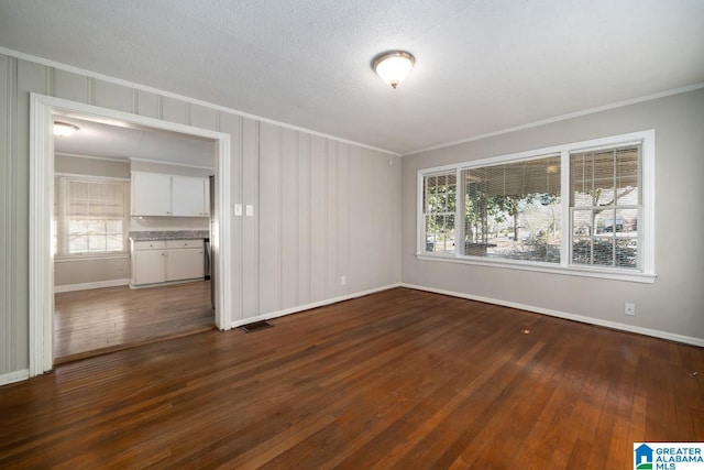 empty room with crown molding, dark hardwood / wood-style flooring, and a textured ceiling