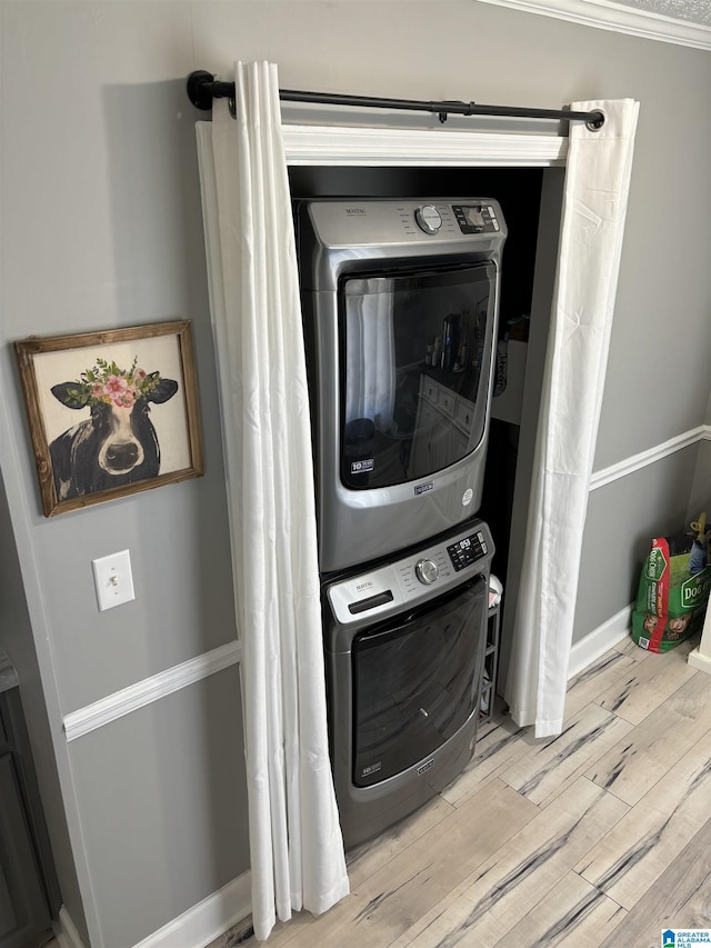 clothes washing area featuring stacked washer and clothes dryer and light hardwood / wood-style floors