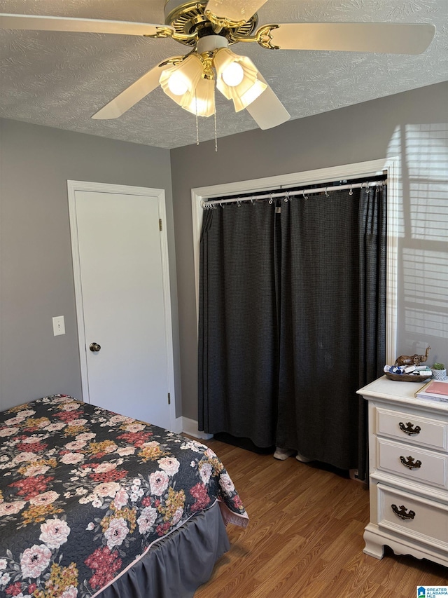 bedroom featuring wood-type flooring, a textured ceiling, and ceiling fan