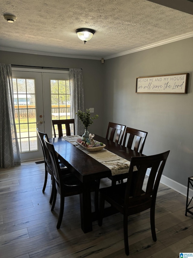 dining space featuring hardwood / wood-style floors, crown molding, french doors, and a textured ceiling