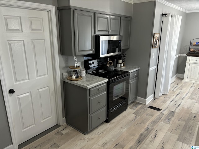 kitchen featuring ornamental molding, light hardwood / wood-style flooring, gray cabinetry, and black / electric stove