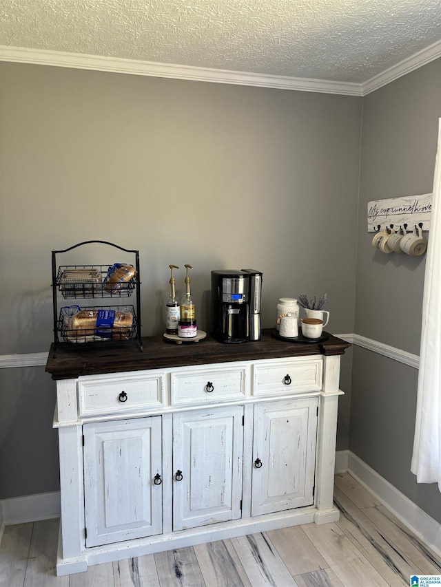 bar with crown molding, a textured ceiling, and light wood-type flooring