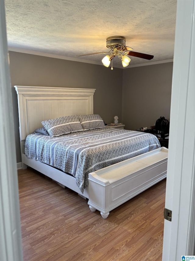 bedroom with crown molding, hardwood / wood-style floors, a textured ceiling, and ceiling fan