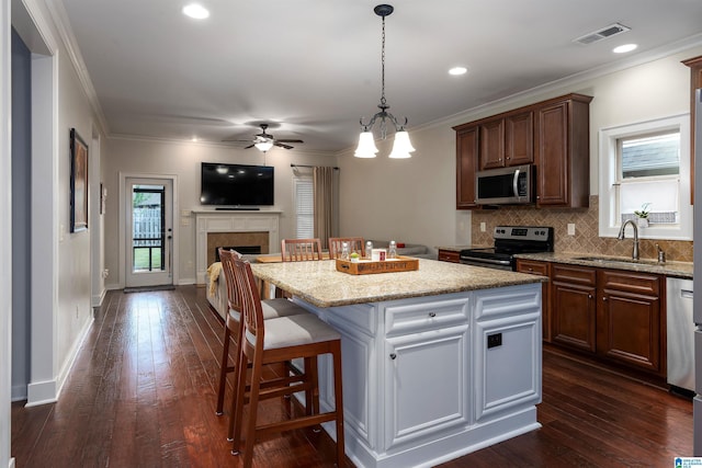 kitchen featuring sink, a kitchen bar, a center island, stainless steel appliances, and light stone countertops