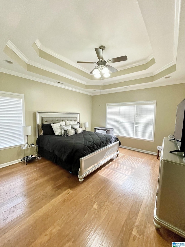 bedroom with a raised ceiling, ornamental molding, hardwood / wood-style flooring, and ceiling fan