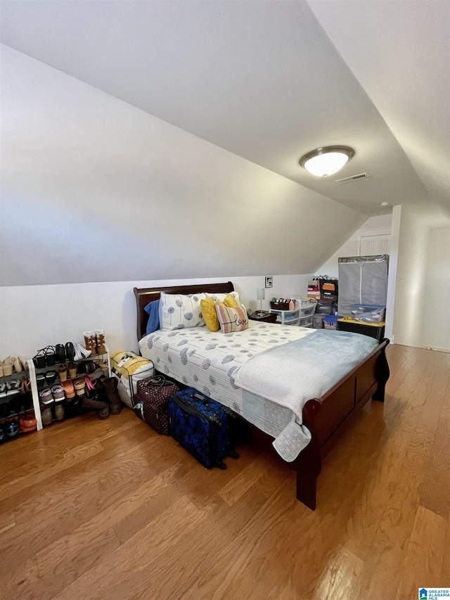 bedroom featuring vaulted ceiling and light wood-type flooring