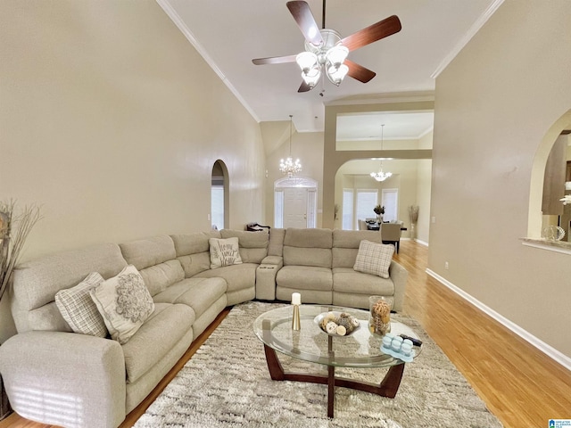 living room featuring crown molding, ceiling fan with notable chandelier, a towering ceiling, and hardwood / wood-style floors