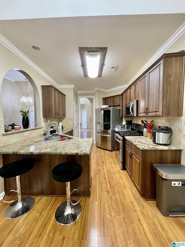 kitchen featuring a kitchen bar, crown molding, light hardwood / wood-style flooring, appliances with stainless steel finishes, and kitchen peninsula