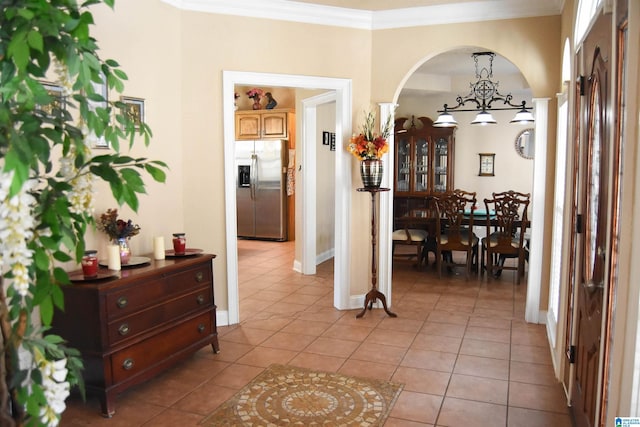 hall with crown molding, a notable chandelier, and light tile patterned floors