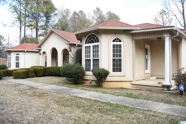 mediterranean / spanish home with a porch and a front lawn