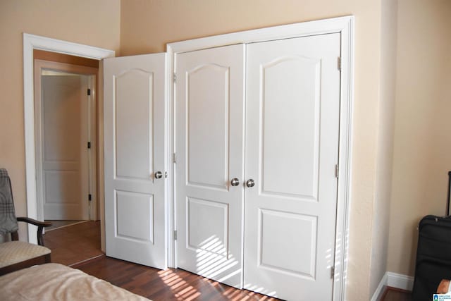 bedroom with dark hardwood / wood-style flooring and a closet