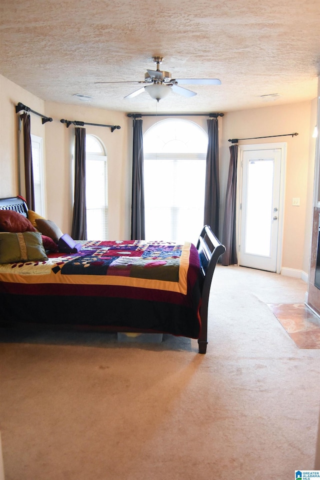 bedroom with light carpet, a textured ceiling, multiple windows, and ceiling fan