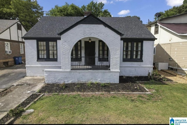 view of front of house with cooling unit, a porch, and a front lawn