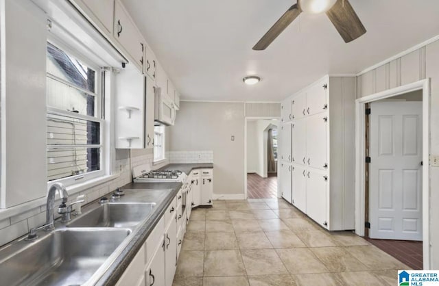 kitchen featuring white cabinetry, sink, light tile patterned floors, and range