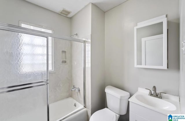 full bathroom featuring vanity, a wealth of natural light, shower / bath combination with glass door, and toilet