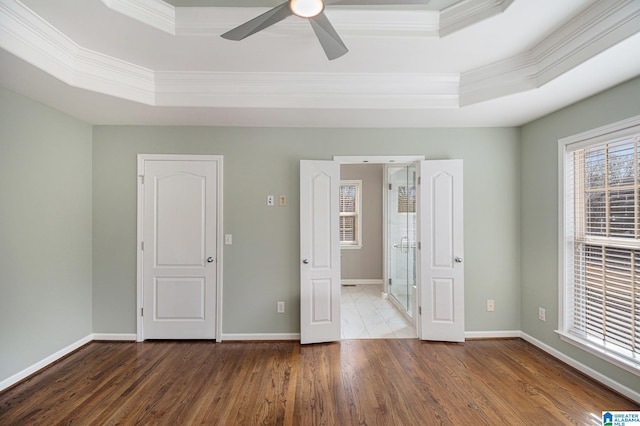 unfurnished bedroom with crown molding, a tray ceiling, dark hardwood / wood-style floors, and ceiling fan