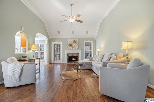 living room featuring crown molding, ceiling fan, high vaulted ceiling, dark hardwood / wood-style floors, and a brick fireplace